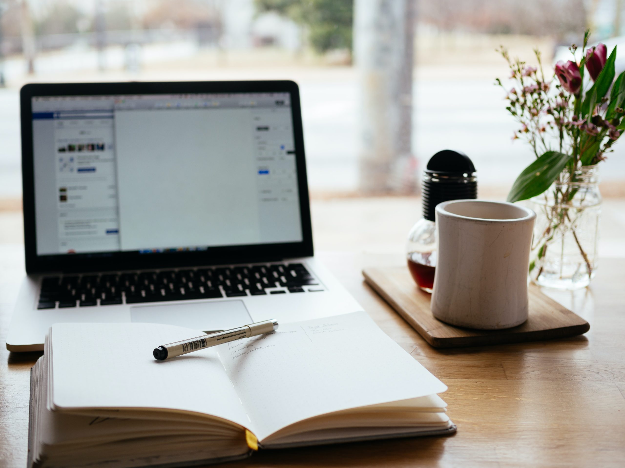 An open laptop next to a cup of coffee