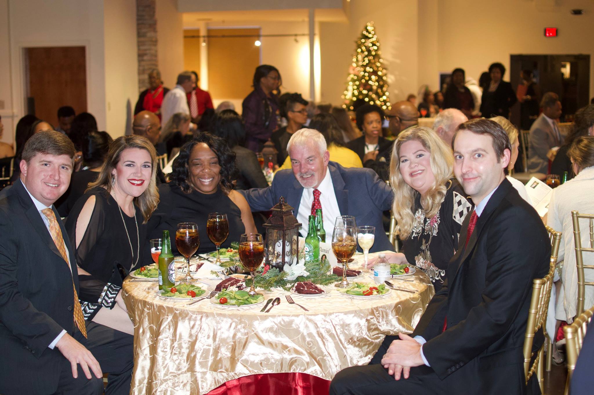 A group of people dressed in formal wear sit together at a round table