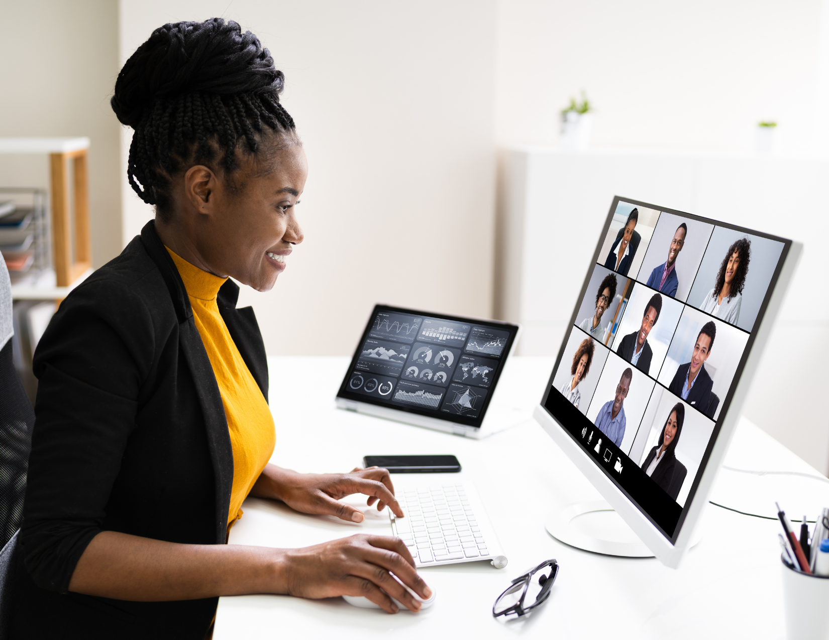 Black women wearing a yellow top sits in front of an open laptop smiling